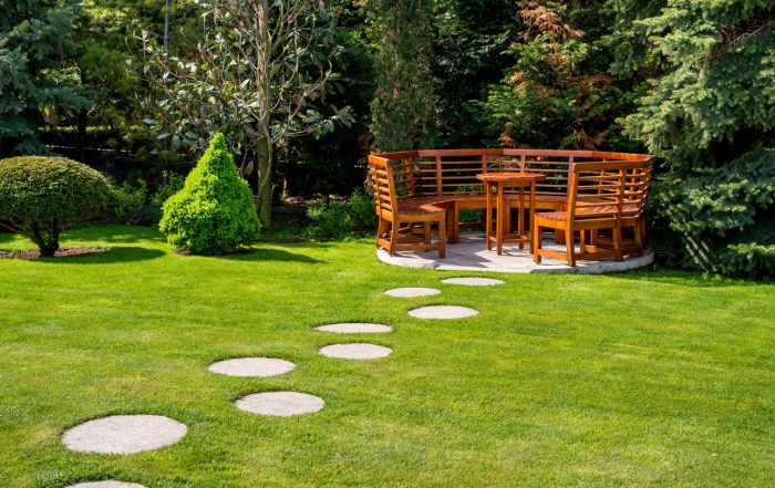 circular stone pathway mixed in with grass leading to wood sitting area